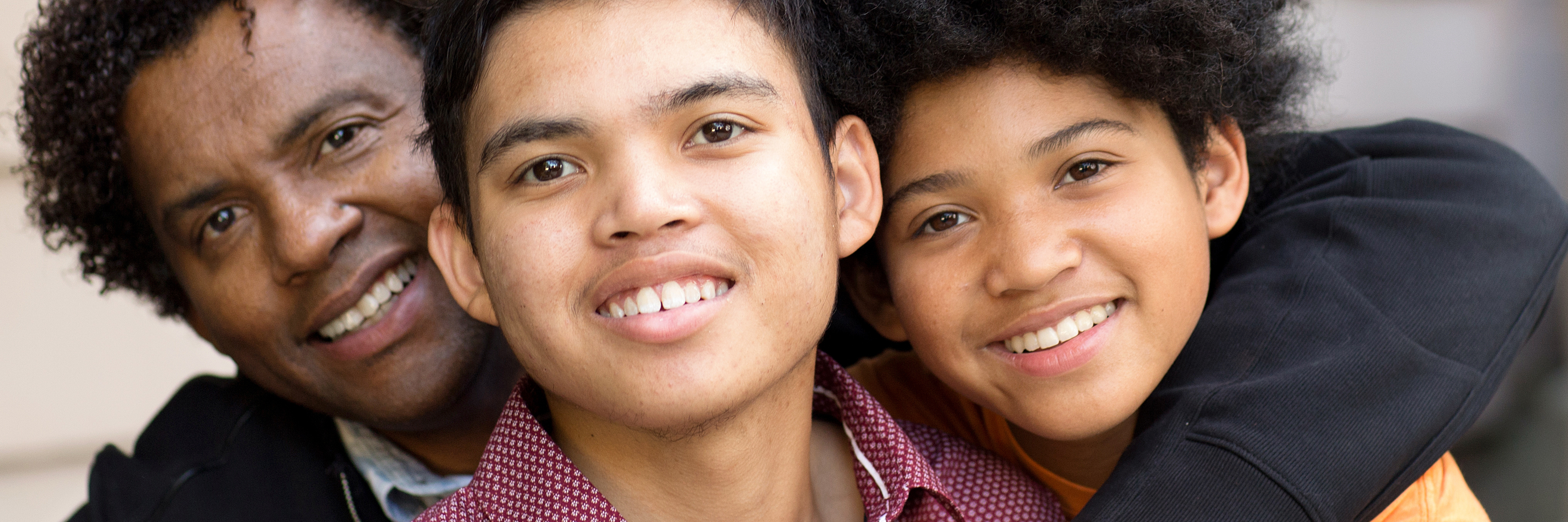 A male provider is hugging two teenaged boys.
